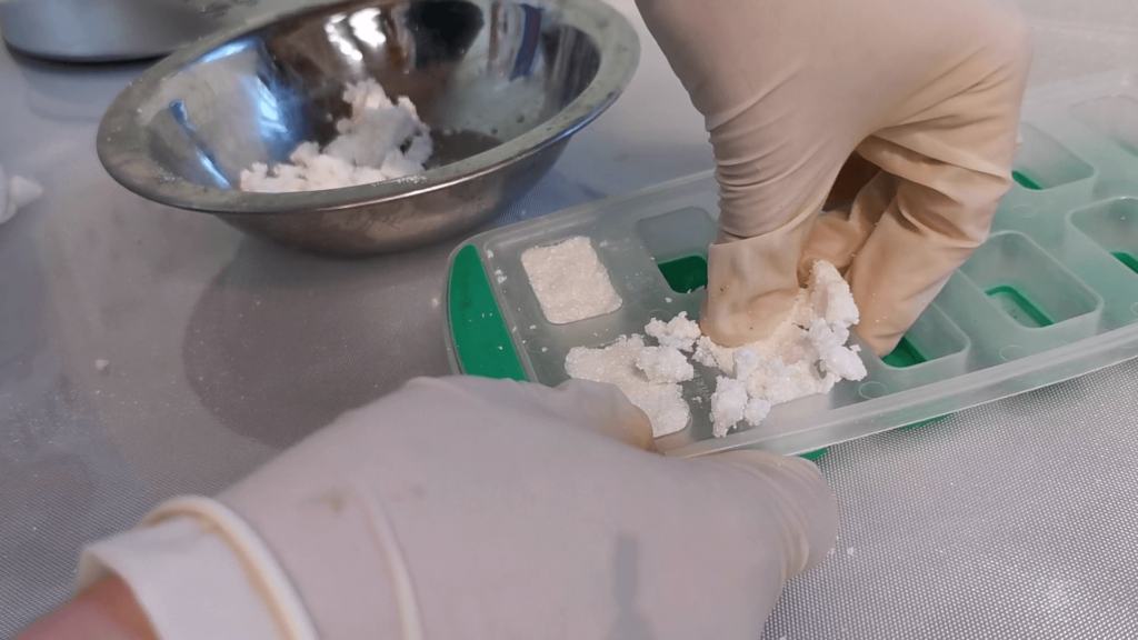 pushing the mixture down into the ice-tray mould